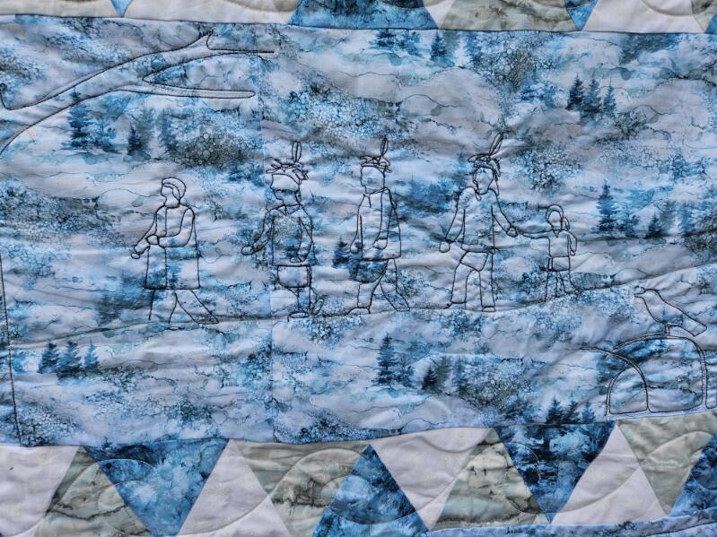 Winter traditions A blue quilt with black stitching depicting people doing traditional winter activities.