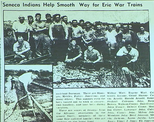An old newspaper with the headline "Seneca Indians Help Smooth the Way for Erie Trains". Beneath headline is the featured image of a crew of railroad workers grouped together for a photo. in the left lower corner is a railroad worker bent over tending to the tracks. two columns of text then are situated beside this image.
